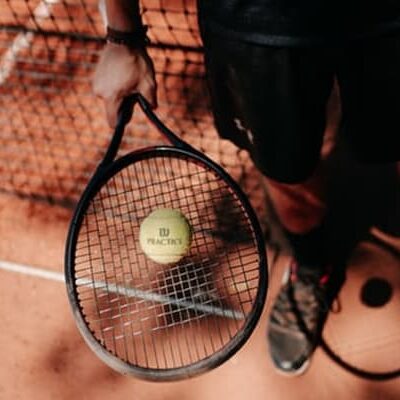person with tennis ball and racket on clay court