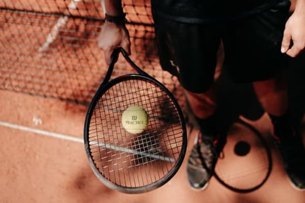 person with tennis ball and racket on clay court