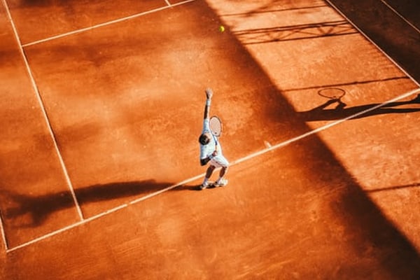 Man playing tennis on clay court